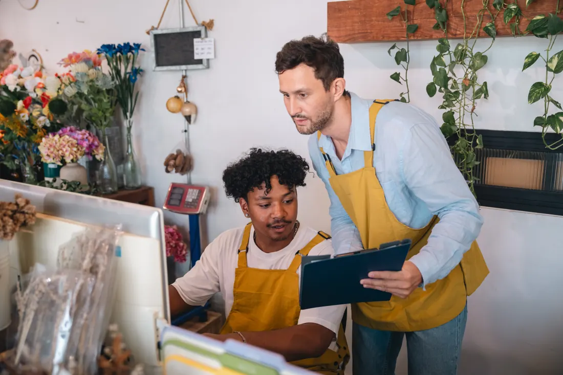 Dos empleados de una tienda planeando un pedido en el mostrador